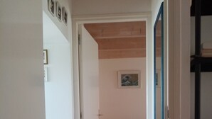 Ein Flur mit Holzboden, einem runden Teppich, einer Holzbank und einem gerahmten Bild an der Wand.