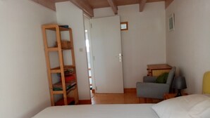 Ein Schlafzimmer mit einem Bett, einem Holzregal, einem Stuhl und einem Schreibtisch.