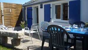 Eine Terrassenfläche mit Esstisch, Stühlen für draußen und einer Steinsitzbank.