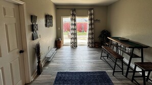 A hallway with a wooden floor, a bench, a table, and a door. - Redrocks Hot Tub Landing Pad (Littleton)