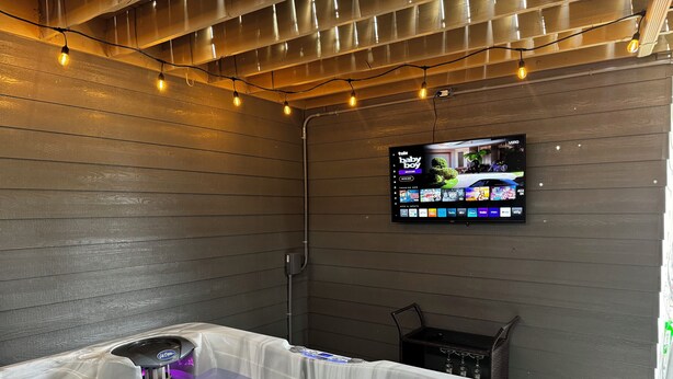 A hot tub with a control panel, a television mounted on the wall, and string lights. - Redrocks Hot Tub Landing Pad (Littleton)