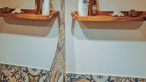 A bathroom with two wooden shelves, each holding toiletries and decorative items. - Agriturismo Li Guira (Stio)