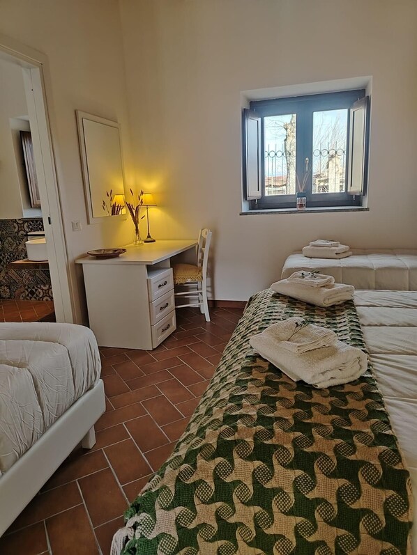 A bedroom with a bed, a desk, a chair, and a window.