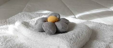 A neatly made bed with white bedding and a gray, textured pillow with a yellow accent.