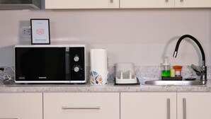 Eine Küche mit Mikrowelle, Spüle und einer Arbeitsplatte mit verschiedenen Gegenständen.