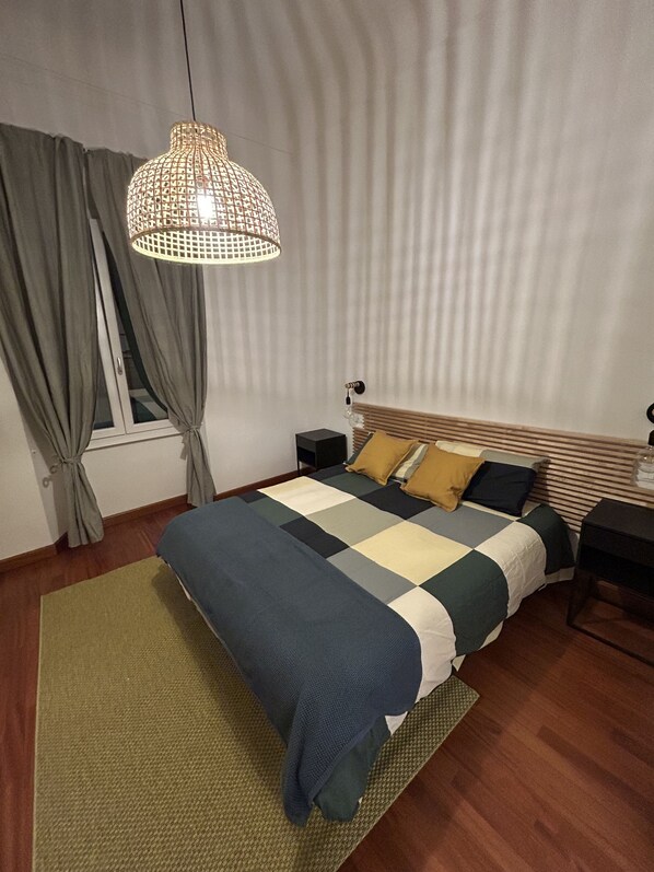 A bedroom with a bed, a nightstand, a lamp, and a window with curtains. - Cozy family apartment near the center, accessible by car. (Firenze)