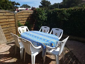 Een terras met tafel en stoelen, omringd door een houten omheining en groen.