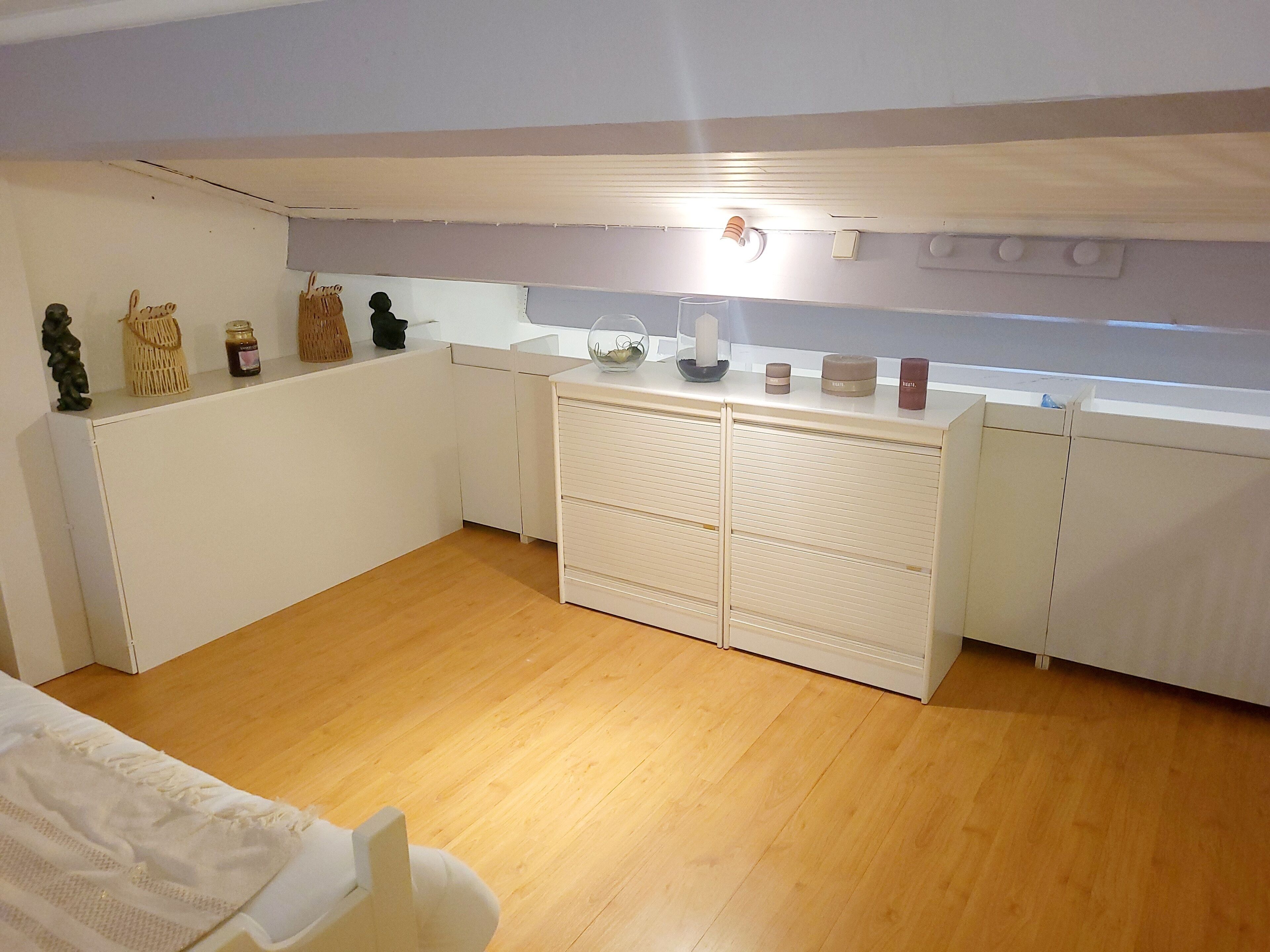 Eine kleine Küche mit weißen Schränken, Holzboden und einer Arbeitsplatte mit Dekoration.