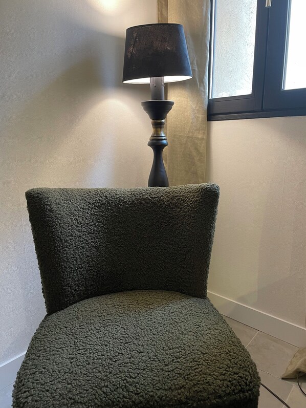 Una silla verde con textura y una lámpara negra al fondo.