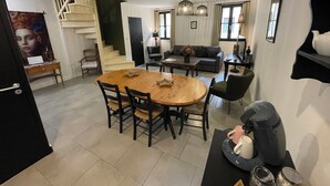 A modern living room with a dining area, featuring a staircase, a sofa, a coffee table, and a coffee machine. - Welcome to Le Trois Six Very nice air-conditioned duplex (Pézenas)