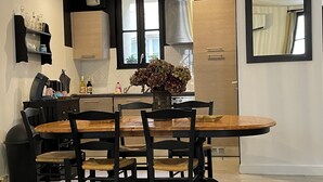 A modern kitchen with a wooden dining table, black chairs, and a vase with flowers. - Welcome to Le Trois Six Very nice air-conditioned duplex (Pézenas)