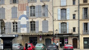 A street with buildings, parked cars, and a person walking. - Welcome to Le Trois Six Very nice air-conditioned duplex (Pézenas)