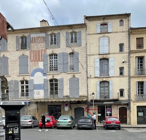 Calle con edificios, coches aparcados y una persona caminando.