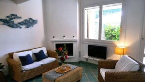 A cozy living room with wicker furniture, a fireplace, and a television.