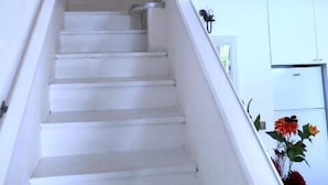 A white staircase with a handrail, leading to a door at the top.