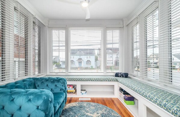 A room with a large window, a blue sofa, and a small bookshelf.