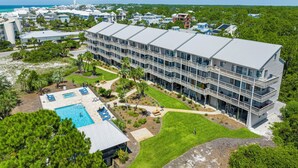 A multi-story hotel with a pool, surrounded by greenery and a view of the ocean. - The Mini Pearl 30A beach studio - Dog Friendly! (Santa Rosa Beach)