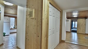 A hallway with wooden paneling, a white door, and a tiled floor.