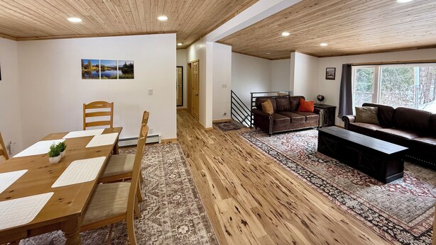 Ein geräumiger Wohnbereich mit Holzboden, einem Esstisch mit Stühlen, einer Couch und einem Couchtisch.