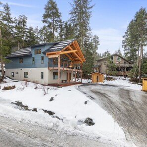 The driveway leads to the home and separate sauna in a wooded residential neighborhood.