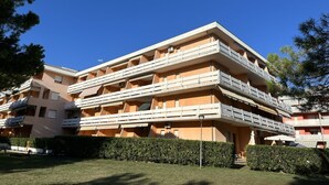 A multi-story building with balconies, a flat roof, and a well-maintained lawn. - Oceanview Apartment With two Terraces (San Michele al Tagliamento)