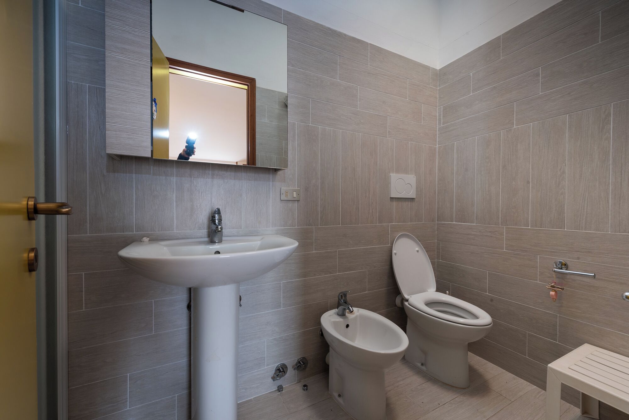 A bathroom with a sink, bidet, toilet, and a mirror above the sink.