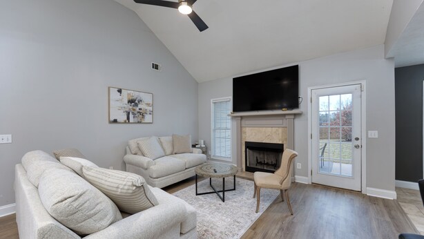 A living room with a fireplace, two sofas, a coffee table, and a TV mounted on the wall.