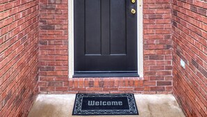 A black front door with a small window above it, set in a brick wall with a white trim.