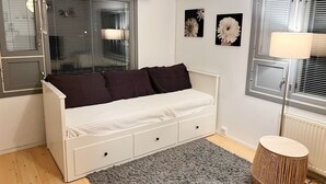 A bedroom with a white bed, dark pillows, a grey rug, a wooden side table, and two wall-mounted air conditioning units. - 1010 Sunny House (Vaasa)