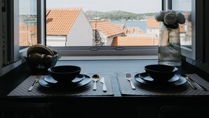 Ein Esstisch mit zwei Schüsseln und Besteck, vor einem Fenster mit Blick auf Gebäude und einen klaren Himmel.