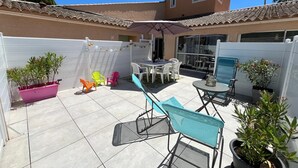 Eine Terrasse mit Tisch und Stühlen, einem kleinen Pool und Topfpflanzen.