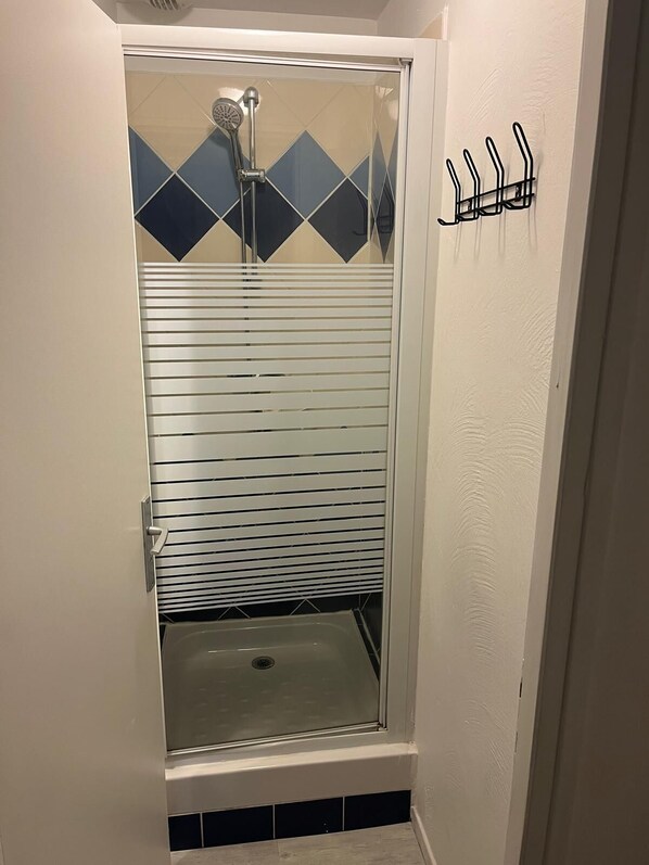 A shower with a glass door, a tiled wall, and a metal towel rack.