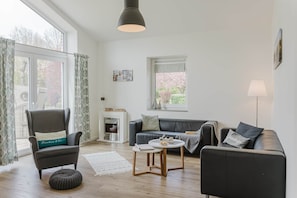 Un salon moderne avec une cheminée, un canapé, un fauteuil et une table ronde.
