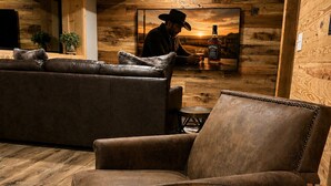 A cozy lounge area with a wooden barrel table, leather sofas, and a rustic wooden wall.