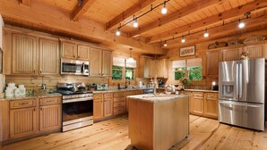 A spacious kitchen with wooden cabinets, stainless steel appliances, and a large island. - Secluded Creekside Cabin - Fire Pit, Deck & Mountain Views, Sleeps 8 (Lake Lure)