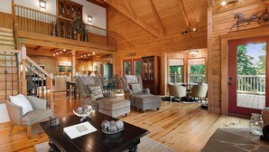 A spacious wooden cabin with a dining area, kitchen, and a balcony with a view. - Secluded Creekside Cabin - Fire Pit, Deck & Mountain Views, Sleeps 8 (Lake Lure)