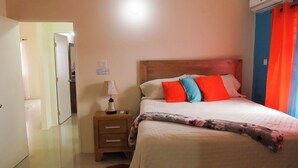 Een hotelkamer met een bed, nachtkastje, lamp en een airconditioning.