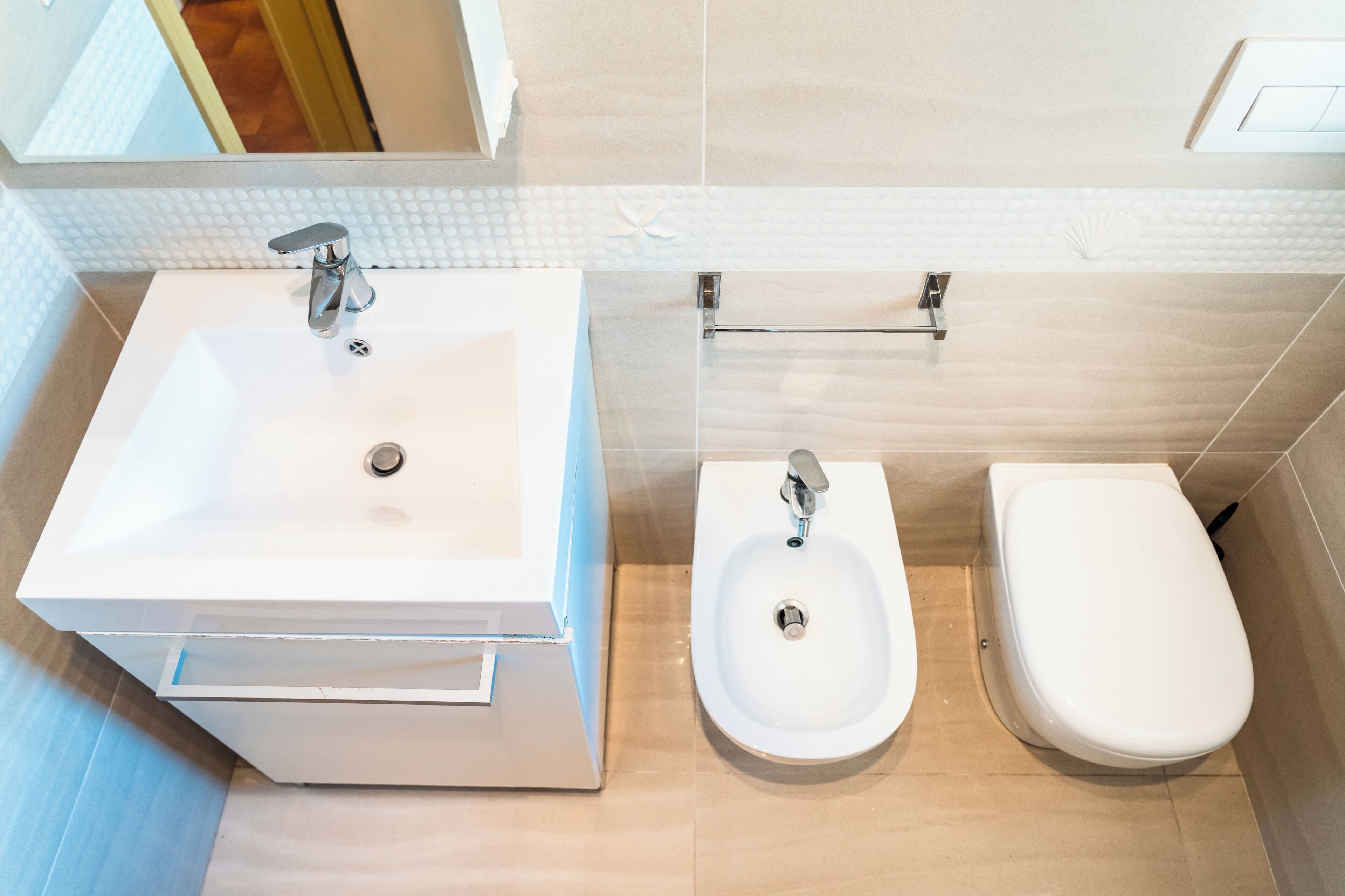 A bathroom with a white sink, bidet, and toilet.