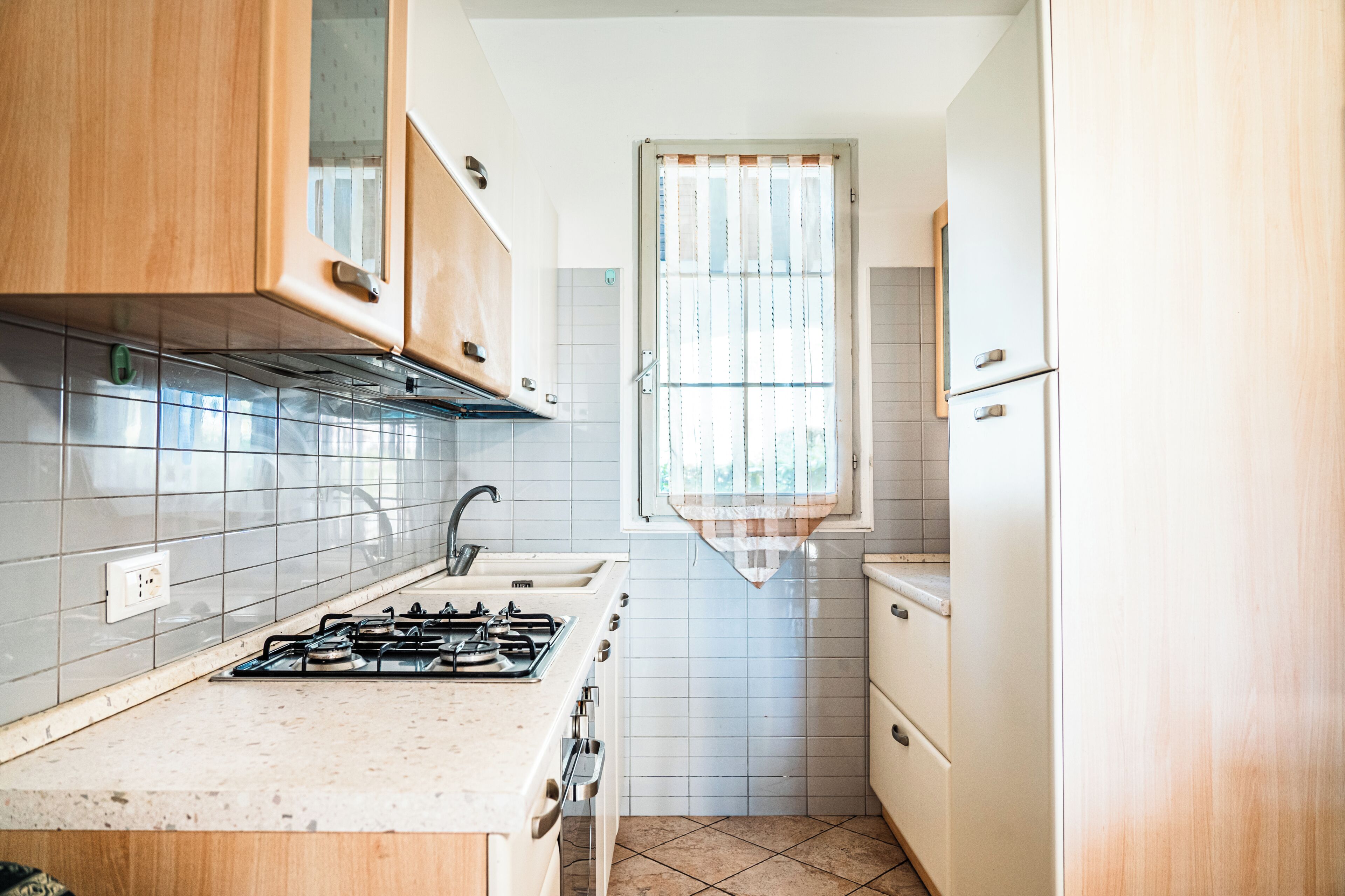 Eine Küche mit Holzausbau, einem Gasherd und einem Fenster mit Vorhängen.