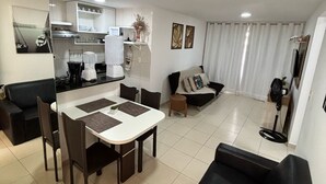 A modern apartment with a dining area, a living room, and a kitchenette.