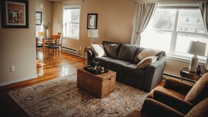 A living room with a sofa, armchairs, a coffee table, and a dining area with chairs and a table.