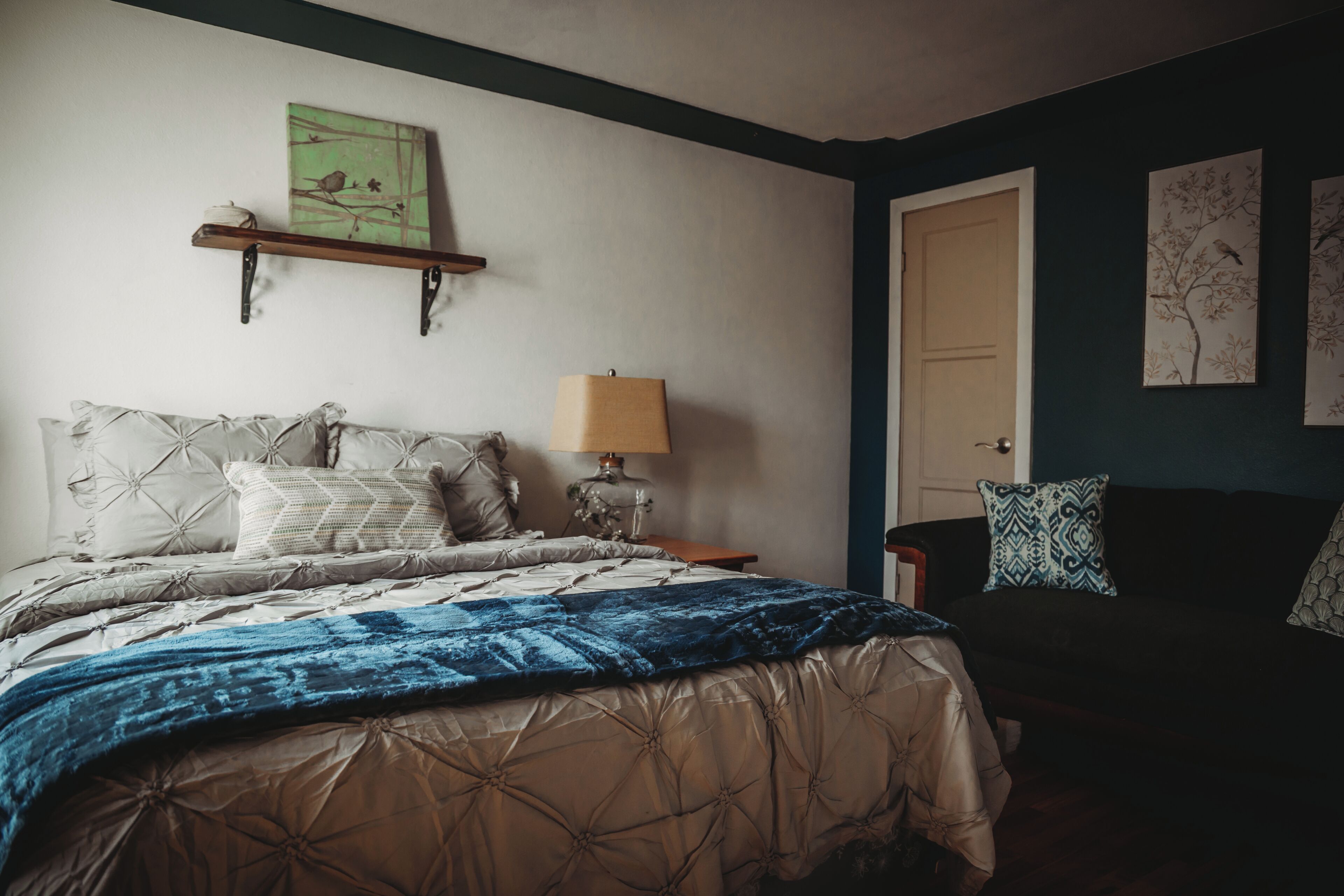A bedroom with a bed, a nightstand, a lamp, and wall art.