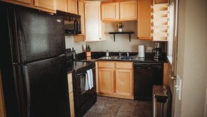 A kitchen with wooden cabinets, a black refrigerator, a microwave, a stove, and a dishwasher.