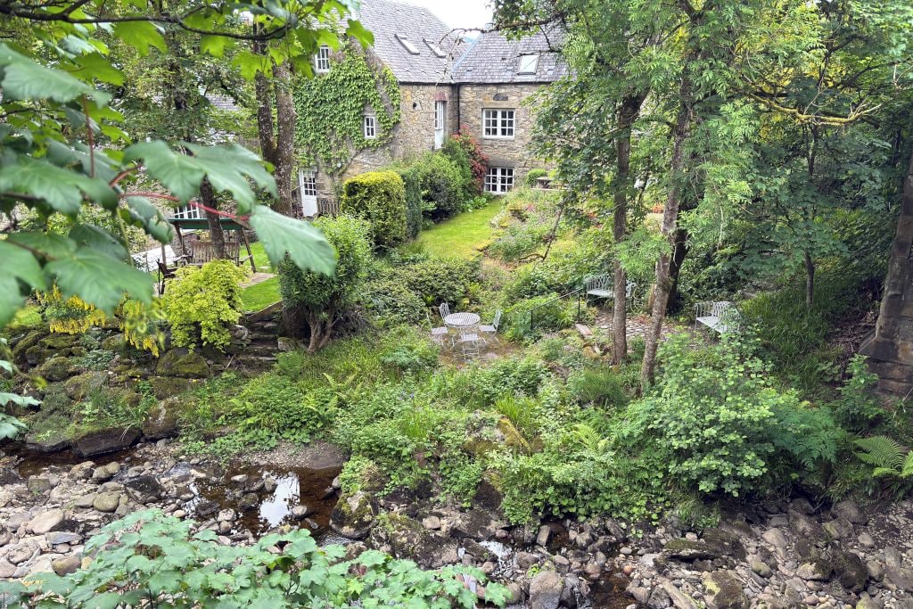 A stone building with a garden and a stream.