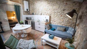 Un ambiente compatto con angolo cottura, divano, tavolo da pranzo e poltrona.