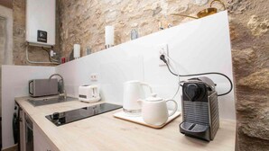 Una cucina moderna con una parete in pietra, un bollitore, una macchina per il caffè, un tostapane e un bollitore su un vassoio.