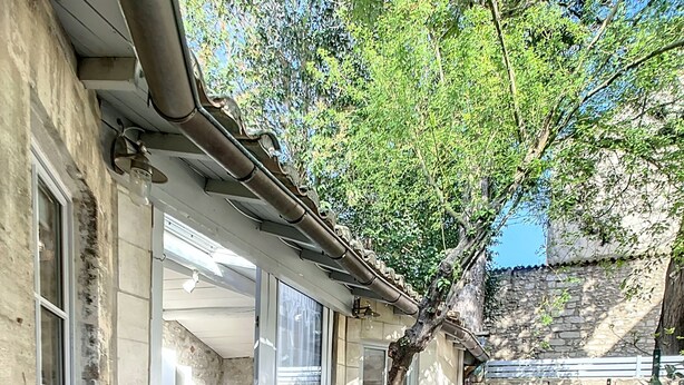 Un edificio in pietra con patio piastrellato, un albero e una pianta in vaso.
