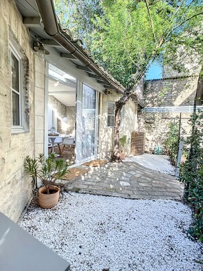 A stone building with a tiled patio, a tree, and a potted plant. - Bright, quiet Mazet in historic center (Avignon)