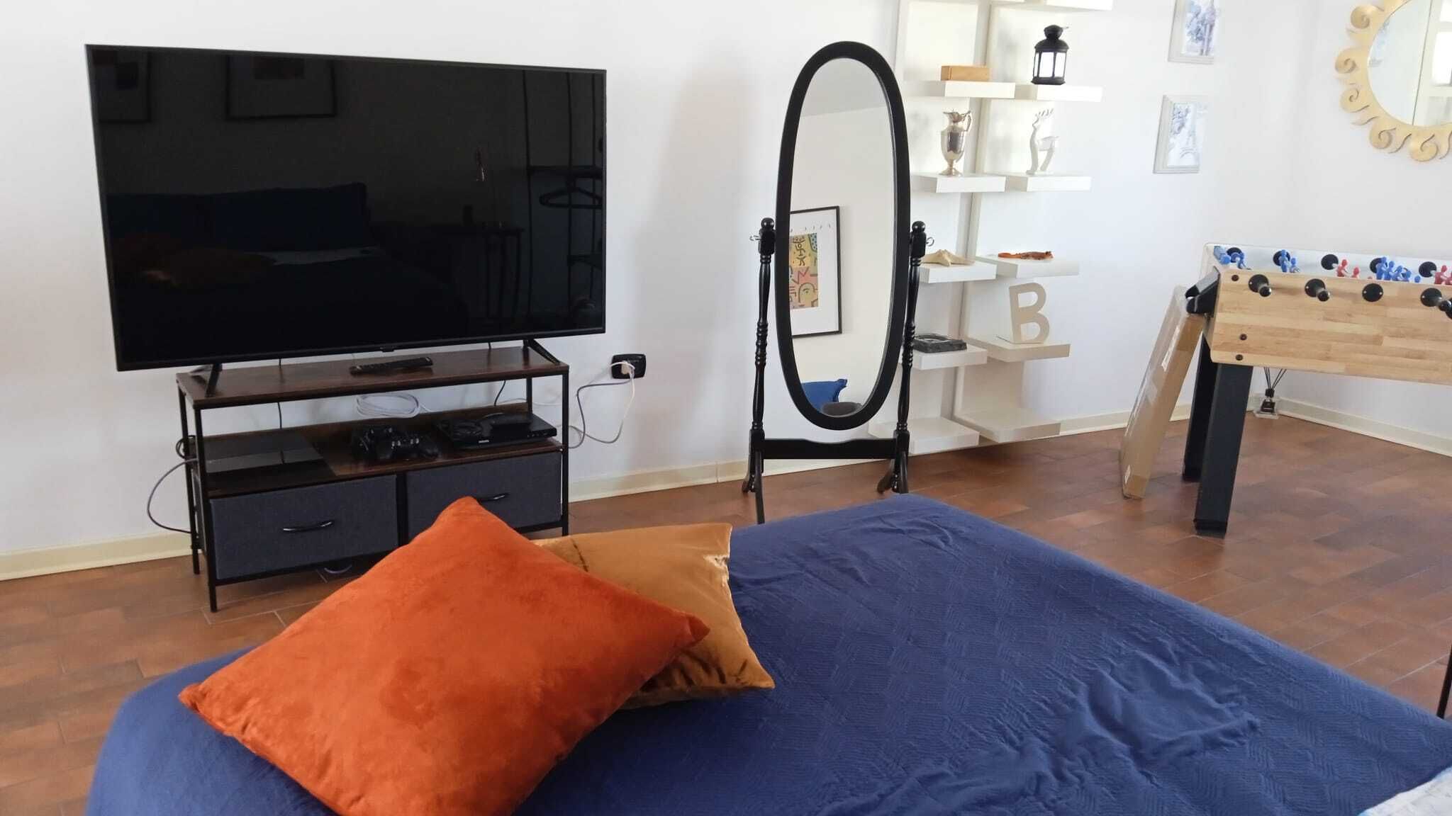 Ein Schlafzimmer mit einem Bett, einem Fernseher auf einem Schrank, einem Spiegel und einem Kicker.