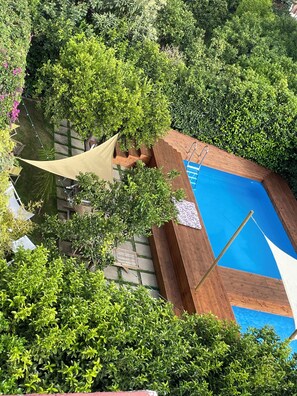 An aerial view of a swimming pool surrounded by lush greenery and wooden decking. - Vesuvius Sky Deluxe Lodge (Boscoreale)